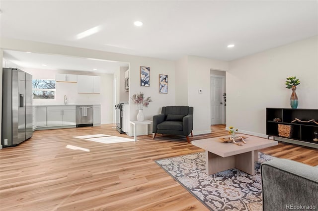 living area featuring baseboards, light wood-type flooring, and recessed lighting