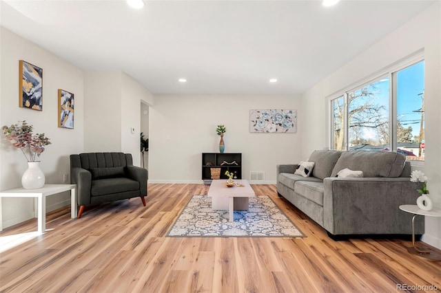 living room with light wood-type flooring, visible vents, baseboards, and recessed lighting