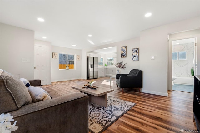 living area with light wood-style flooring, baseboards, and recessed lighting