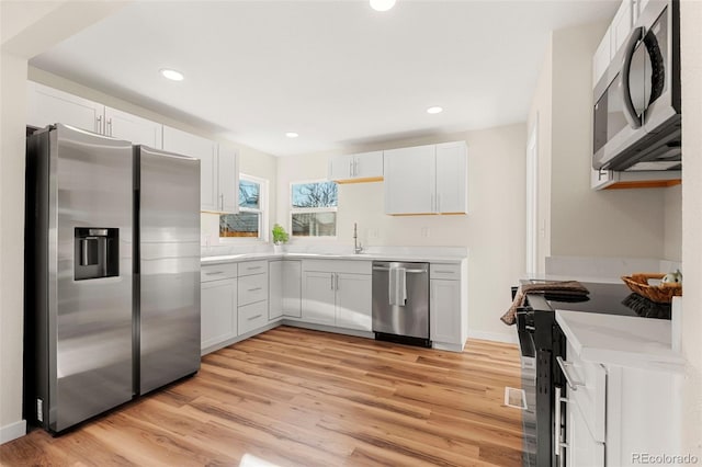 kitchen featuring stainless steel appliances, light wood-type flooring, light countertops, and a sink