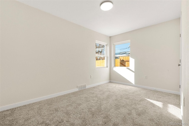 unfurnished room featuring carpet, visible vents, and baseboards