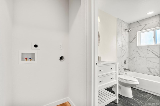 bathroom with washtub / shower combination, marble finish floor, toilet, and baseboards