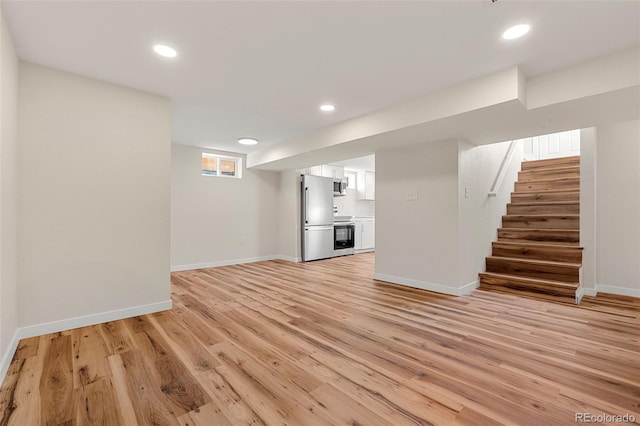 unfurnished living room featuring stairway, light wood-style flooring, and baseboards