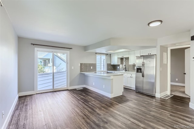 kitchen with kitchen peninsula, stainless steel refrigerator with ice dispenser, dark hardwood / wood-style flooring, and white cabinetry