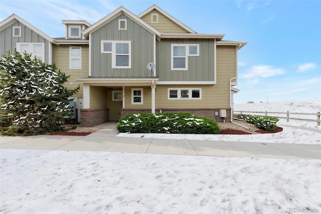 view of front of home featuring board and batten siding, brick siding, and fence