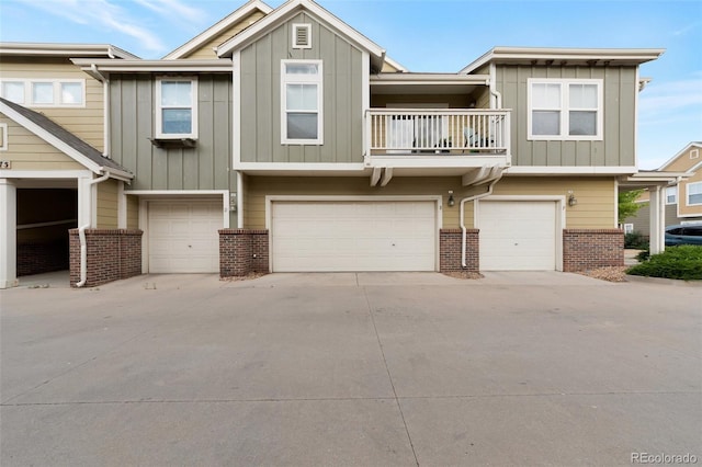 multi unit property with a garage, driveway, brick siding, and board and batten siding