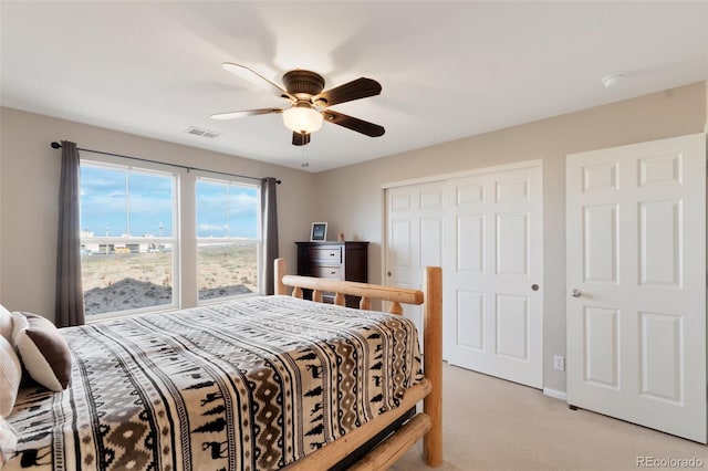 bedroom with a closet, visible vents, light carpet, ceiling fan, and baseboards