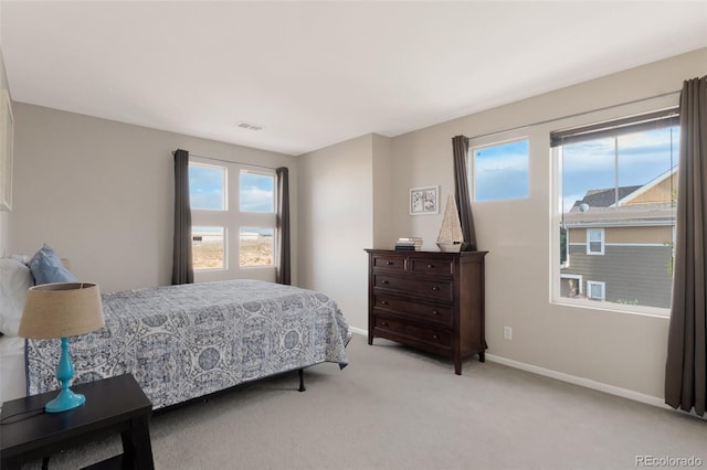 bedroom with visible vents, light carpet, baseboards, and multiple windows