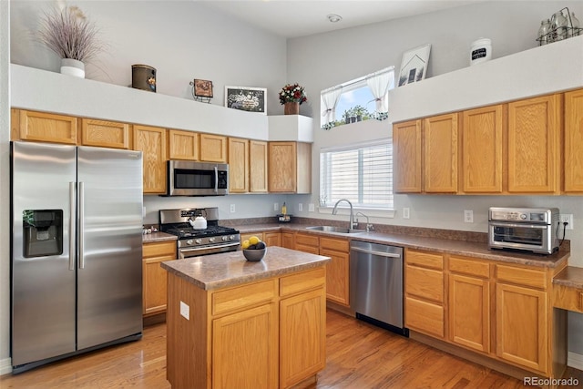 829 Sanctuary Cir, Longmont, CO 80504 - kitchen featuring appliances with stainless steel finishes, a high ceiling, a kitchen island, and light wood finished floors