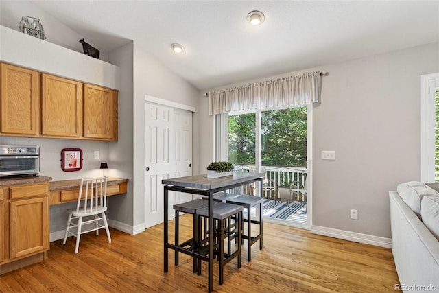 829 Sanctuary Cir, Longmont, CO 80504 - dining space featuring built in study area, vaulted ceiling, and light wood-style floors