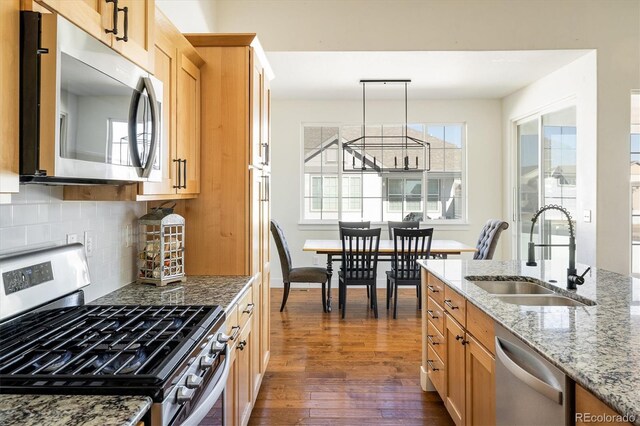 kitchen with decorative light fixtures, sink, dark hardwood / wood-style flooring, light stone counters, and stainless steel appliances