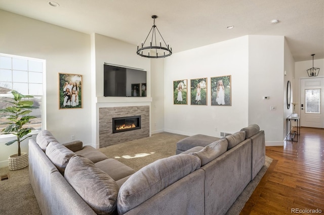 living room with a tiled fireplace, a chandelier, and dark hardwood / wood-style flooring