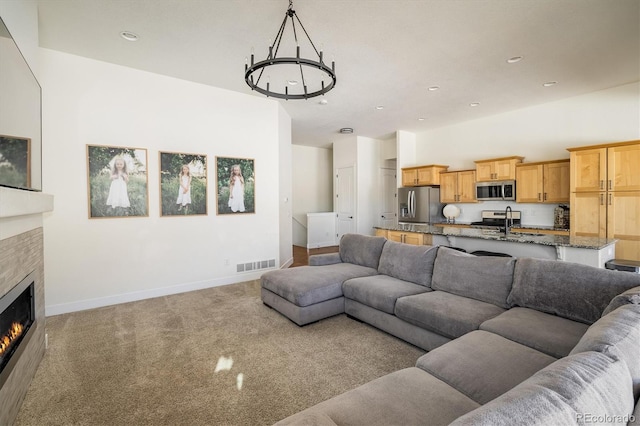 carpeted living room with sink and a tile fireplace