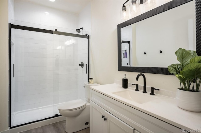 bathroom with hardwood / wood-style flooring, vanity, toilet, and a shower with shower door