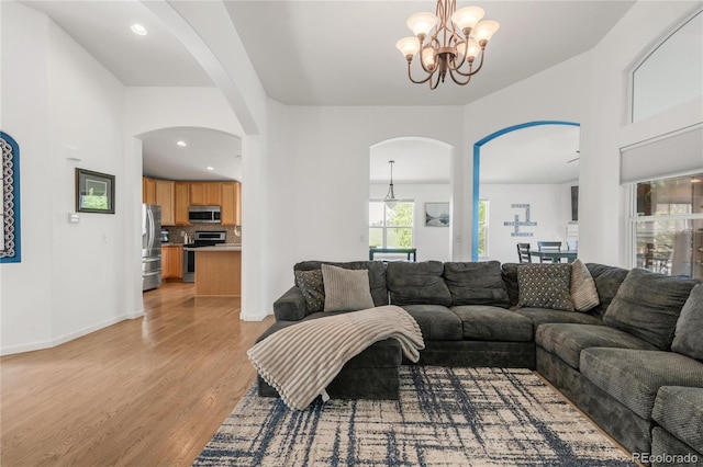 1510 S De Gaulle Cir, Aurora, CO 80018 - living room featuring arched walkways, light wood finished floors, and a chandelier