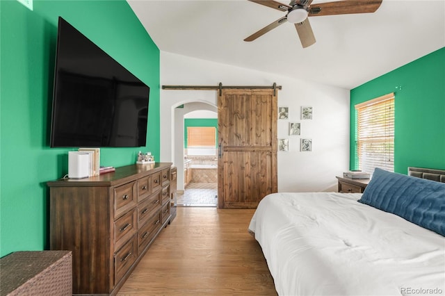 1510 S De Gaulle Cir, Aurora, CO 80018 - bedroom with vaulted ceiling, wood finished floors, a barn door, arched walkways, and ceiling fan
