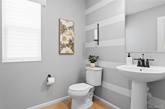 half bathroom with wood finished floors, baseboards, and toilet