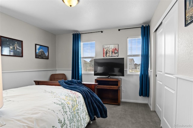 carpeted bedroom with a wainscoted wall and a closet