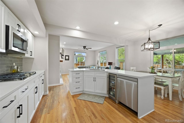 kitchen with beverage cooler, a sink, white cabinets, and stainless steel appliances