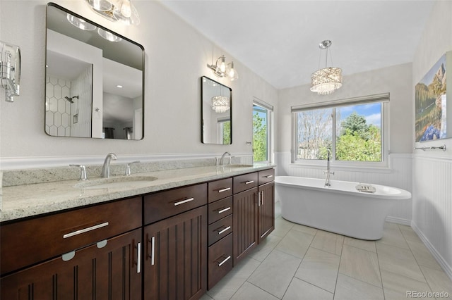 bathroom with a sink, wainscoting, double vanity, and a freestanding bath