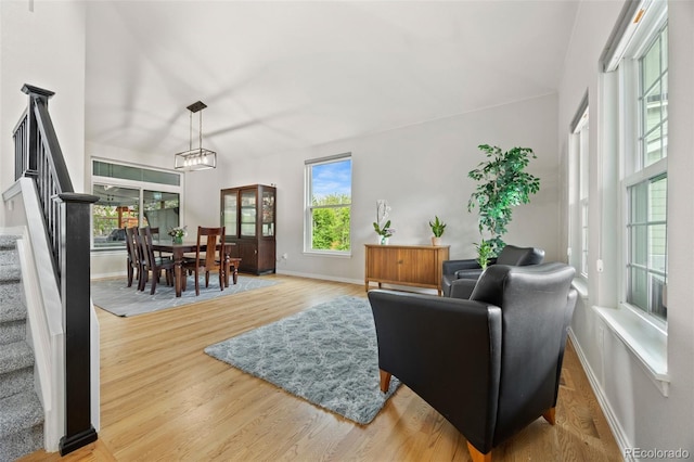 living area with baseboards, wood finished floors, and stairway