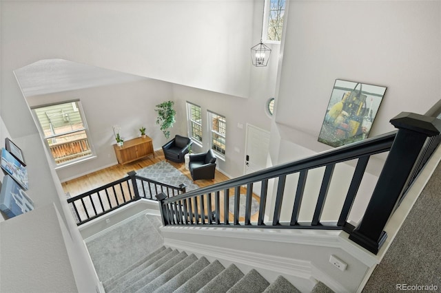 stairs with baseboards, plenty of natural light, and a high ceiling