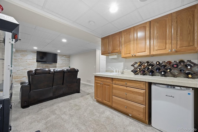 kitchen with light carpet, fridge, recessed lighting, brown cabinets, and a sink