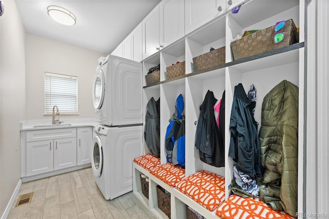 interior space with visible vents, stacked washer / dryer, baseboards, a sink, and cabinet space