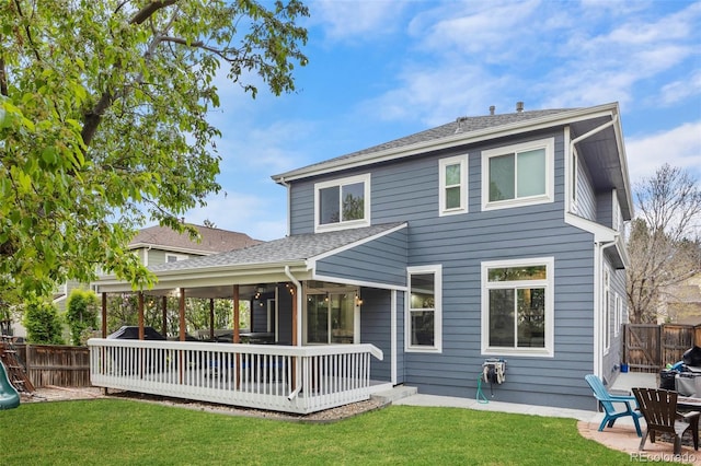 rear view of house featuring a lawn, a patio area, fence, and a wooden deck