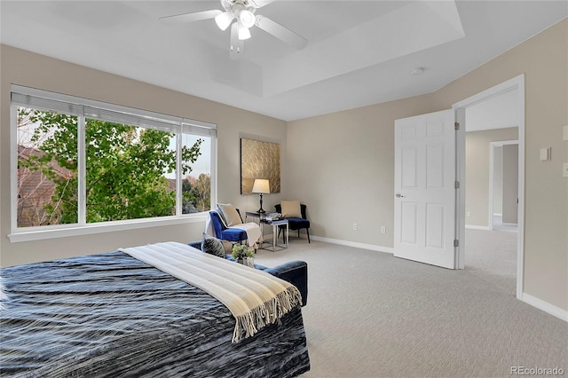 carpeted bedroom featuring baseboards, a ceiling fan, and a tray ceiling