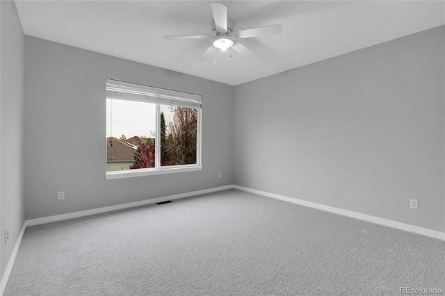 carpeted empty room with baseboards, ceiling fan, and visible vents