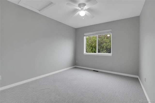 carpeted spare room featuring baseboards, attic access, ceiling fan, and visible vents