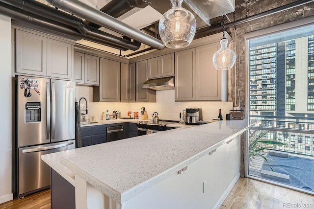 kitchen featuring decorative light fixtures, gray cabinets, light stone countertops, and stainless steel appliances