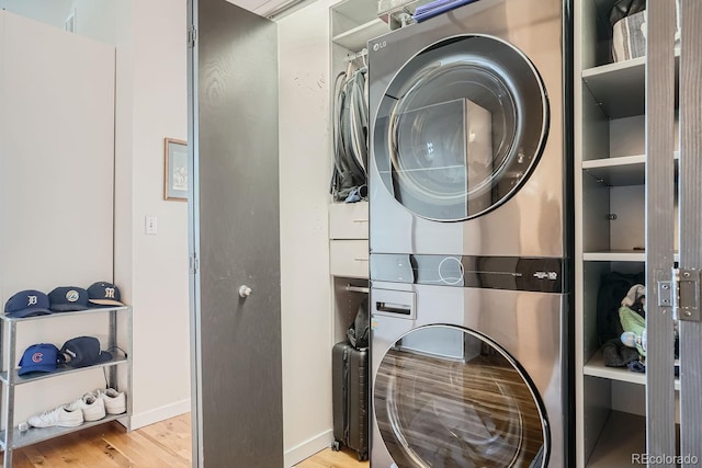 laundry room with light hardwood / wood-style floors and stacked washer / drying machine