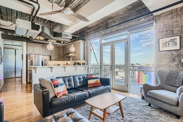 living room featuring a healthy amount of sunlight, french doors, ceiling fan, and light hardwood / wood-style floors