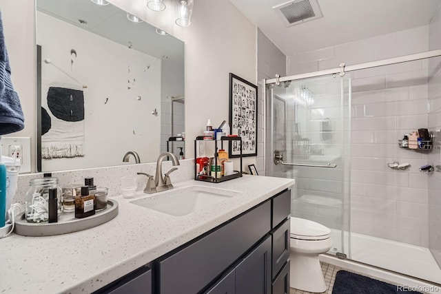 bathroom featuring tile patterned floors, vanity, toilet, and a shower with shower door