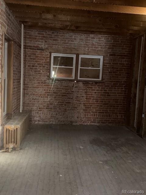 interior space with brick wall and hardwood / wood-style floors