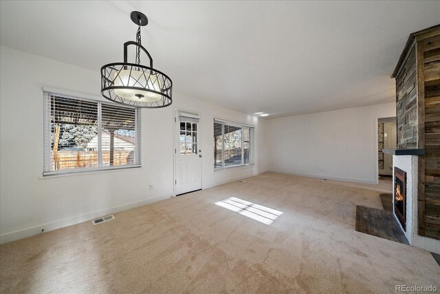 unfurnished living room with carpet flooring, a healthy amount of sunlight, and a fireplace