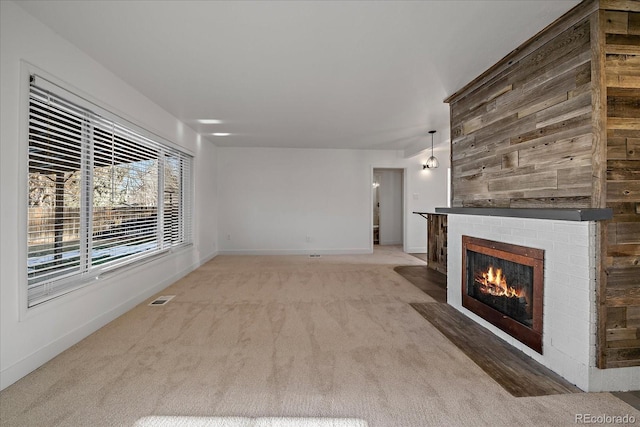 unfurnished living room featuring baseboards, visible vents, a fireplace, and light colored carpet