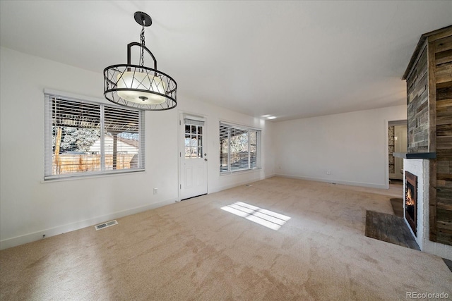 unfurnished living room featuring baseboards, a fireplace, visible vents, and carpet floors