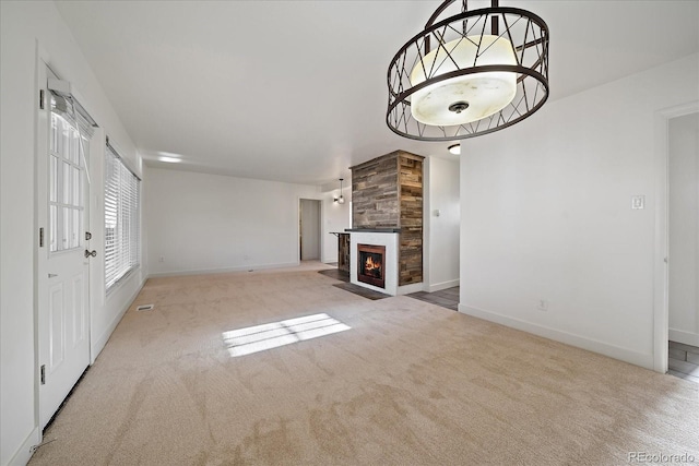 unfurnished living room featuring a fireplace with flush hearth, baseboards, and carpet