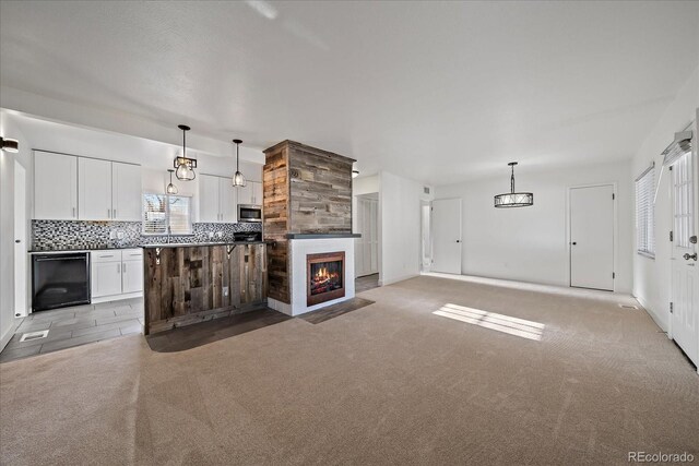 kitchen with white cabinets, backsplash, light carpet, stainless steel microwave, and open floor plan