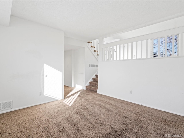 carpeted empty room with a textured ceiling