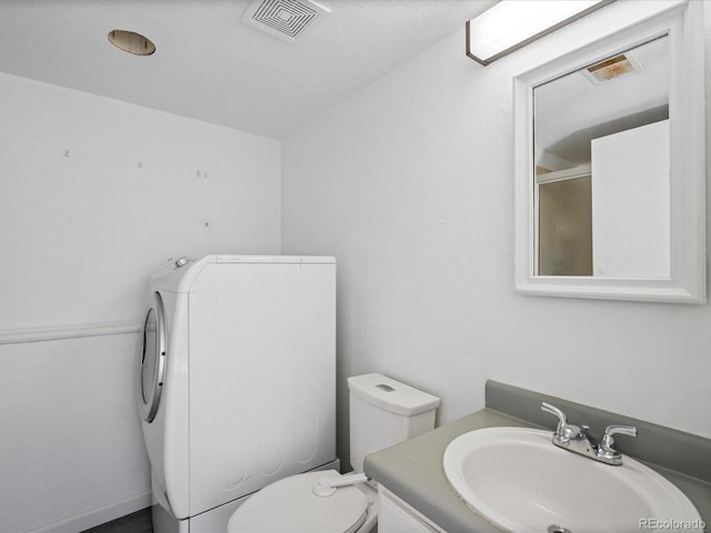 bathroom with vanity, washer / dryer, an enclosed shower, and toilet