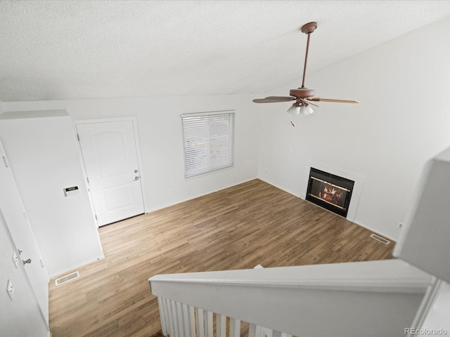 staircase featuring hardwood / wood-style flooring, ceiling fan, lofted ceiling, and a textured ceiling