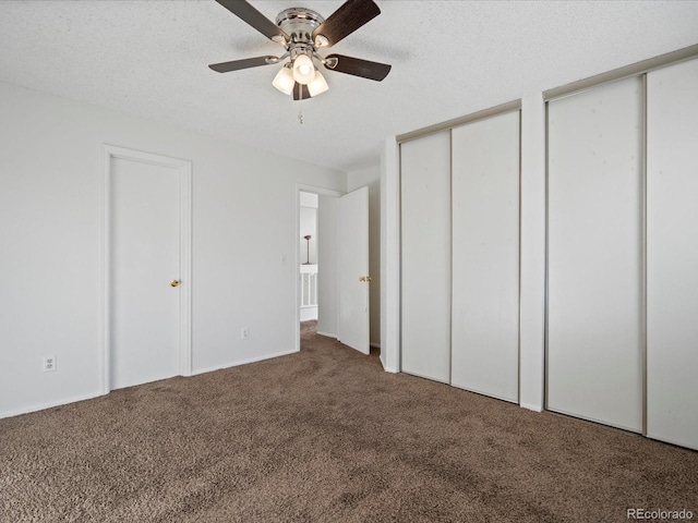 unfurnished bedroom with ceiling fan, a textured ceiling, carpet floors, and multiple closets