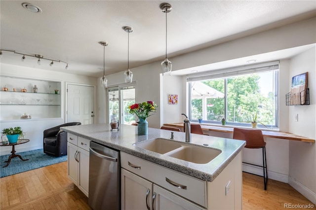 5983 W Indore Pl, Littleton, CO 80128 - kitchen with stainless steel dishwasher, light wood-type flooring, hanging light fixtures, a center island with sink, and white cabinetry