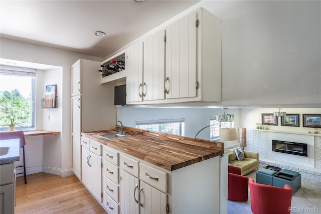 5983 W Indore Pl, Littleton, CO 80128 - kitchen with light wood-type flooring, plenty of natural light, wood counters, and a fireplace