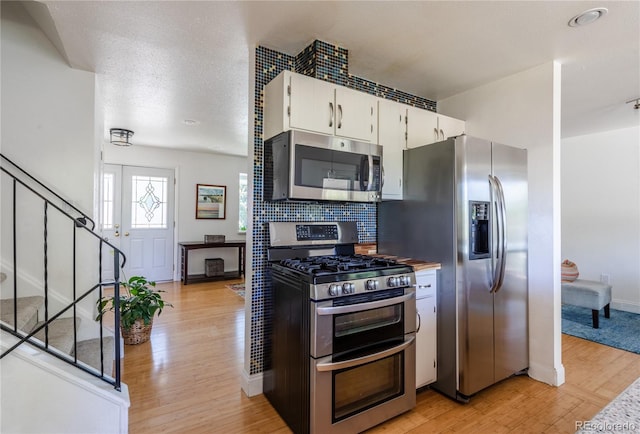 5983 W Indore Pl, Littleton, CO 80128 - kitchen featuring stainless steel appliances, light wood-style flooring, white cabinetry, backsplash, and light countertops