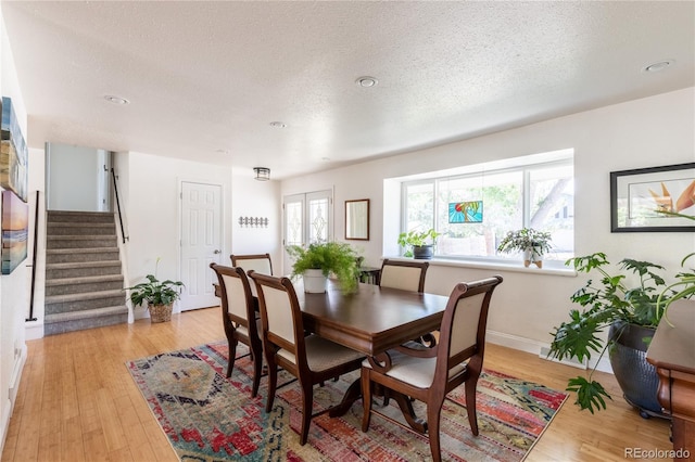 5983 W Indore Pl, Littleton, CO 80128 - dining room featuring a textured ceiling, stairs, and light wood-style floors